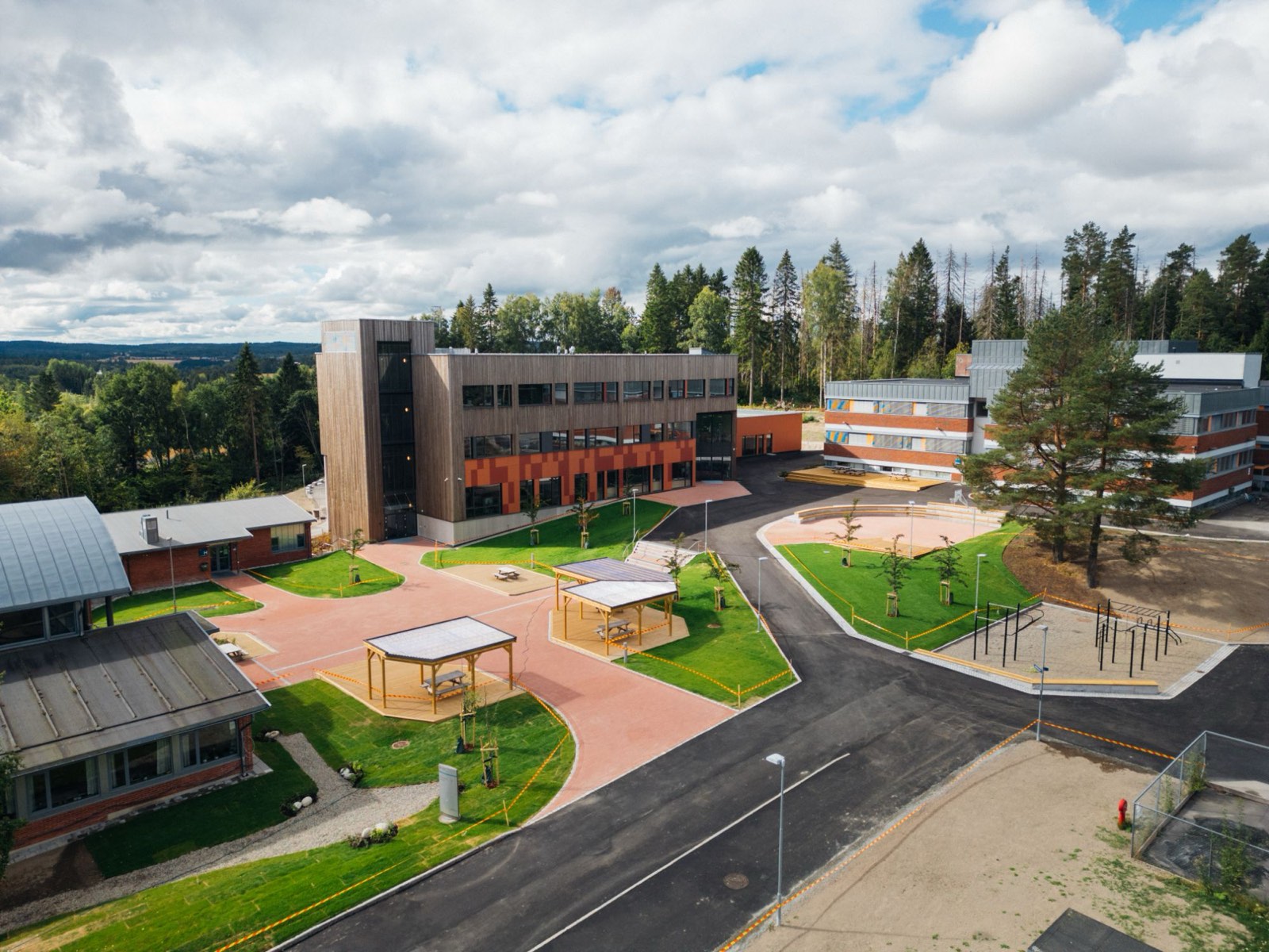 Ferdig skolegård med belegning, plen og paviljonger