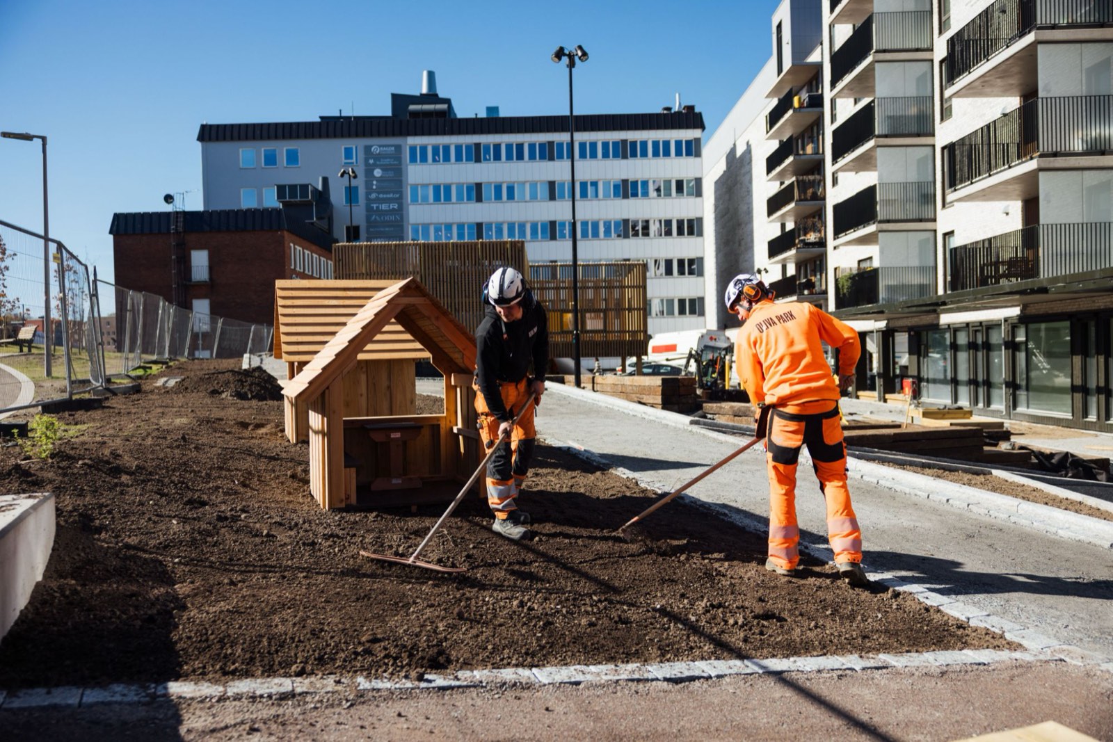 To fagarbeidere fra Oliva Park raker jord på et uteområde